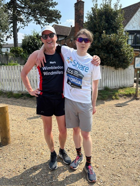Student Georgia stands in her running gear with her arm around fellow runner