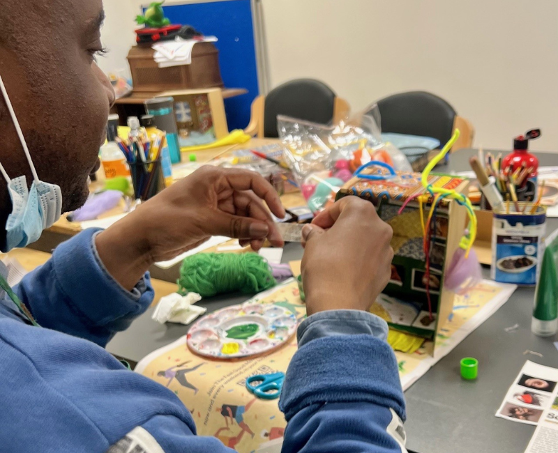 Close up of a man's hands as he creates items to put inside his shoebox house