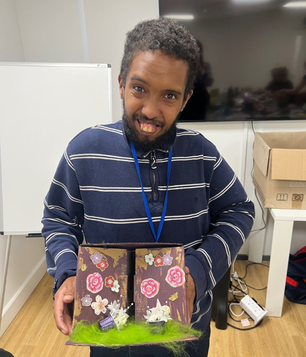 A man stands smiling holding his shoebox