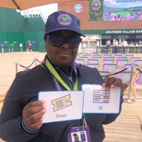 Anna-Marie stands holding her communication cards outside Wimbledon to help communicate to the crowds and scan their tickets