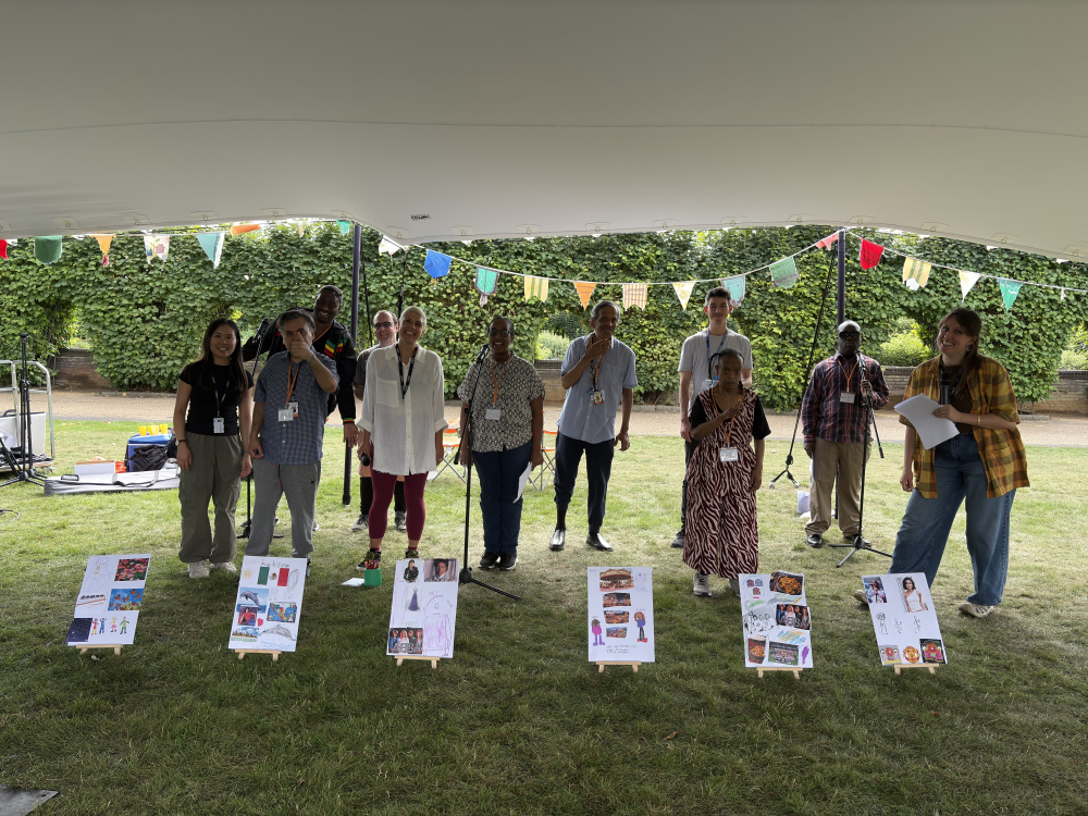 A group stand under a marquee in front of artworks they've created to celebrate what a wonderful world means to them