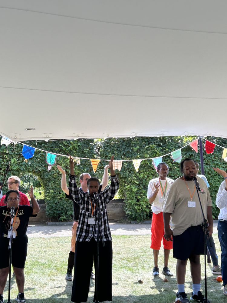 A group stand near microphones under a marquee