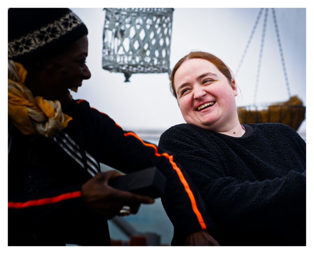 Close up of a young woman who is sitting in a chair laughing to someone next to her