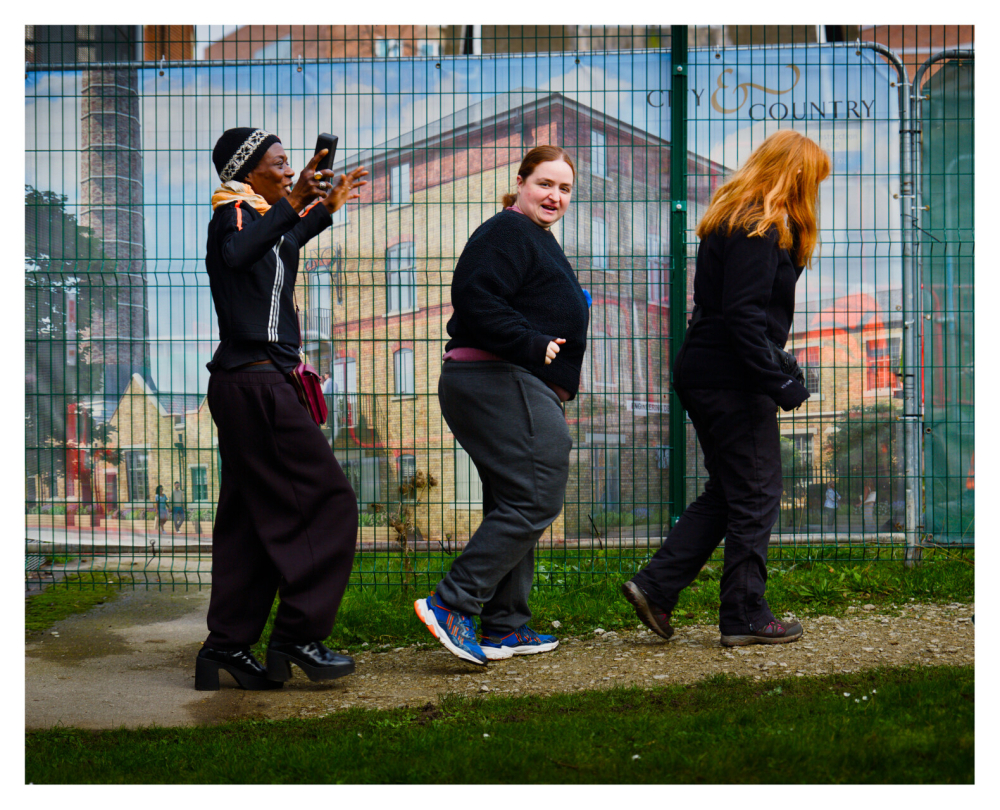 Three people walk along in single file on front of a mural painted wall, it's part of a fun movement activity