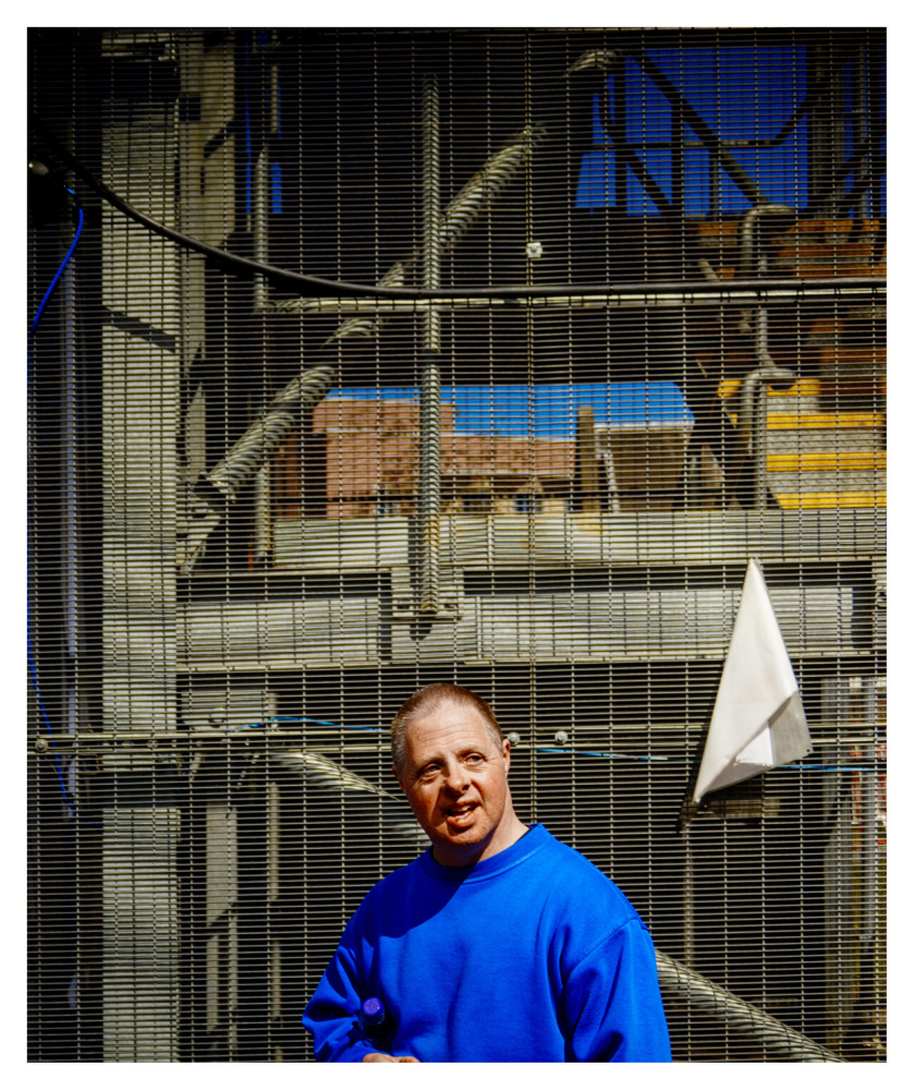 Top of a man in a blue top and above him shed and scaffolding