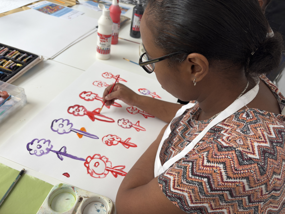 A lady sits drwaing stick figures in different colours