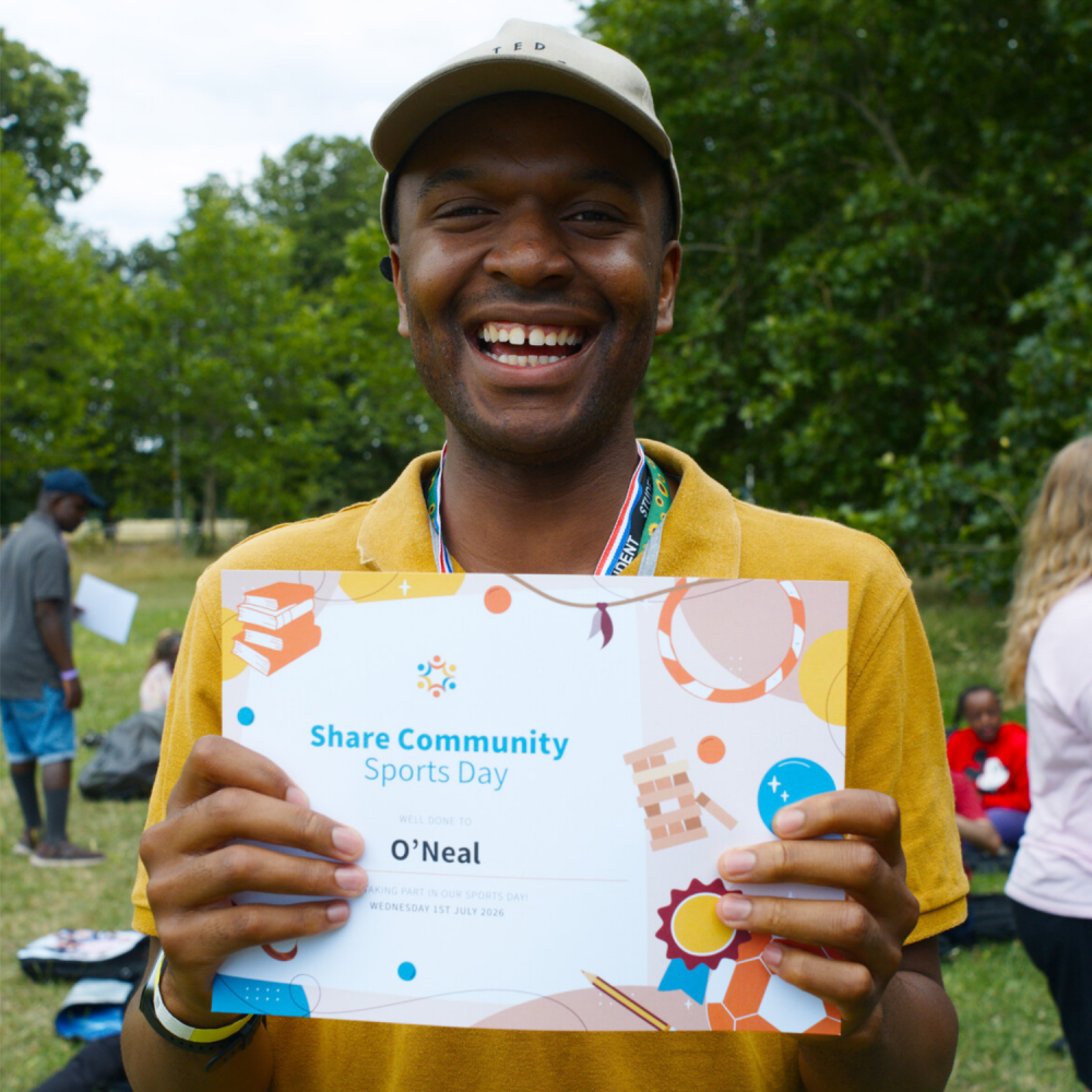 A student smiles and proudly holds up his certificate
