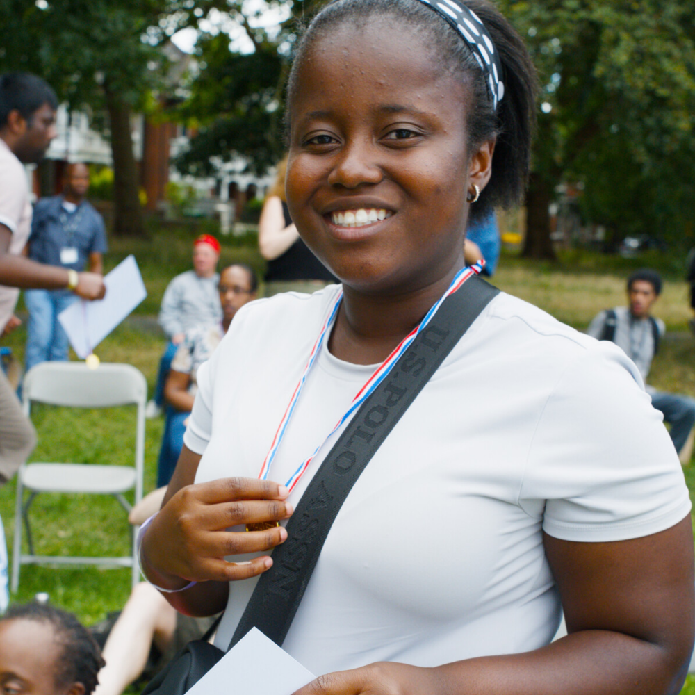 Close up of a Share student, a young woman who is holding her certificate in one hand and her medal in the other (it's round her neck)