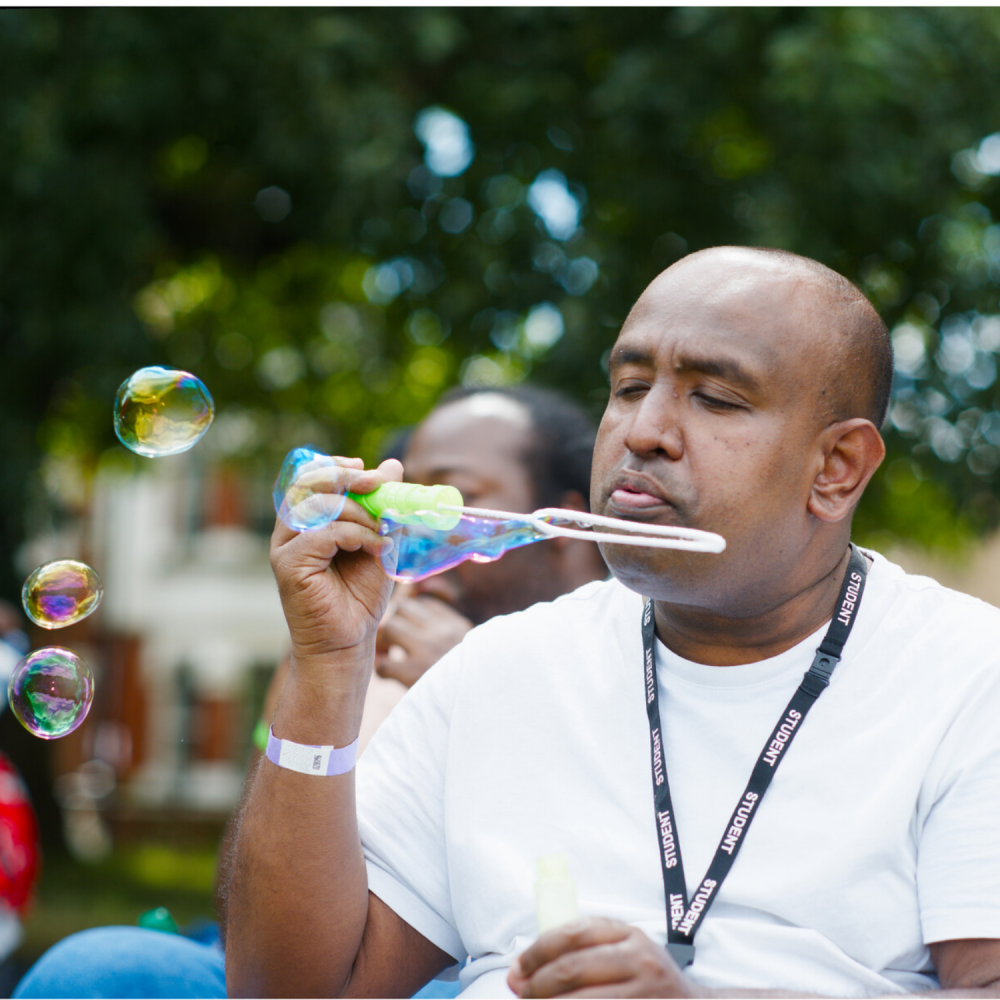 Close up of a man blowing bubbles with a wand and bottle