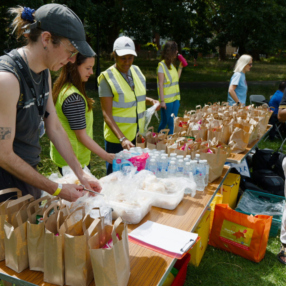A groupf of staff and volunteers man a table with lunch and snack bags