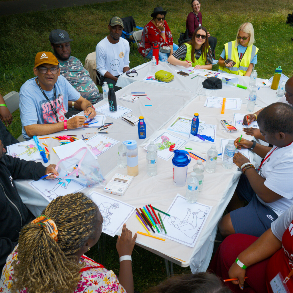 Shot of a crafts table in the park and people witting around it chilling out