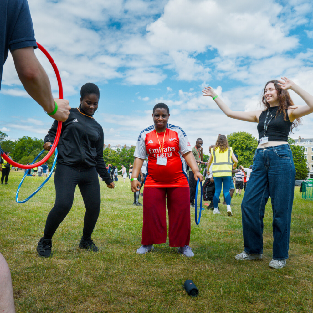 A group stand doing hoola hooping - you can see three people