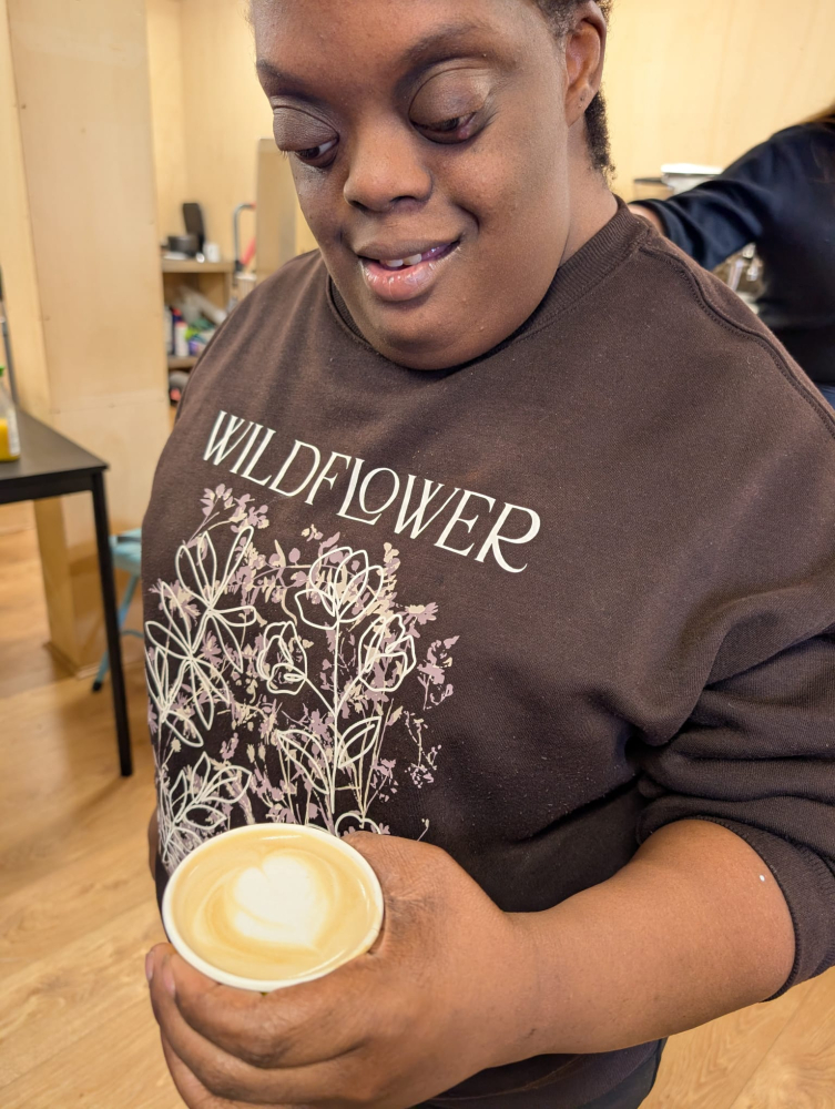 A close up of a woman looking at a barista coffee she's just made