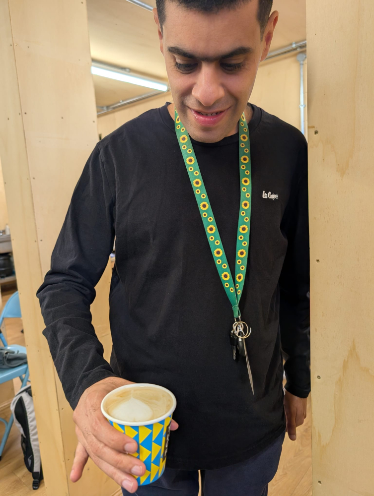 A close up of a young man looking at a barista coffee she's just made