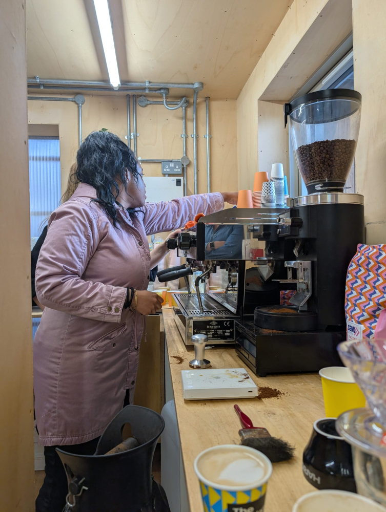 A woman stands operating a barista machine