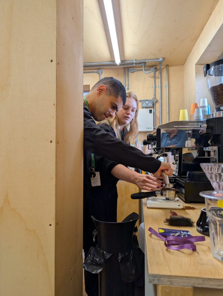 A man stands in front of a barista machine preparing a coffee