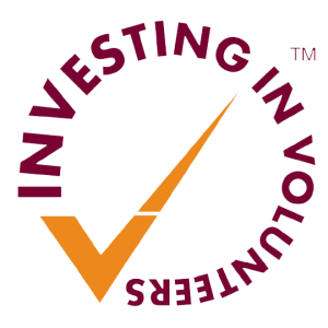 Logo for Investing in Volunteers, purple text on orange tick