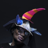 Close up photo of an lady with a learning disability adopting a serious look, modelling her home-made pointed red, yellow and blue hat