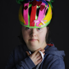 Close up of adult woman with Down's syndrome modelling a pink, yellow and green bike helmet