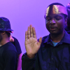 Share student with gold headband faces the camera with closed eyes, his hand is raised with palm facing the camera