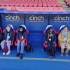 A group of Share students sit in the dugout at Crystal Palace FC, smiling at the camera