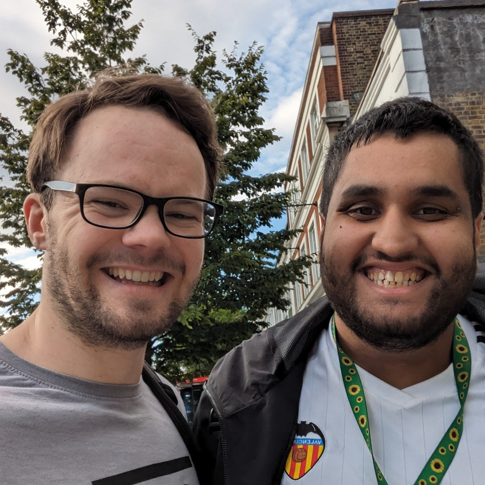 Two men stand smiling for a selfie