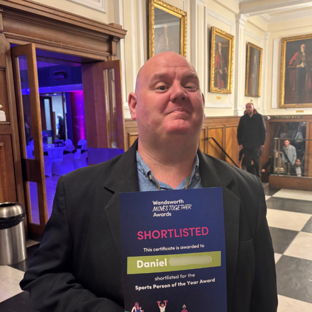 Share student Daniel stands proudly outside an awards event holding a certificate with his name and "shortlisted"