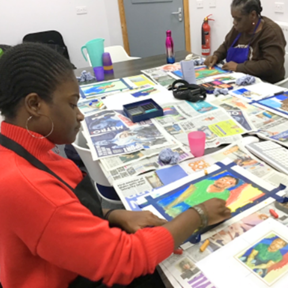 Two ladies who are Share students sit painting at a table