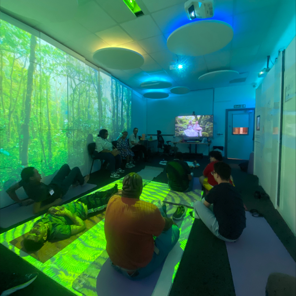 A group lie on the floor meditating in a room filled with green and blue light