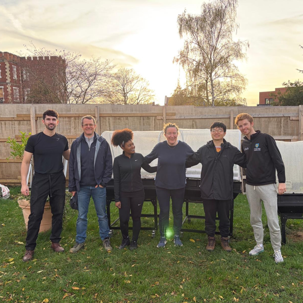 A group of corporate volunteers stand in a line in the Share garden smiling