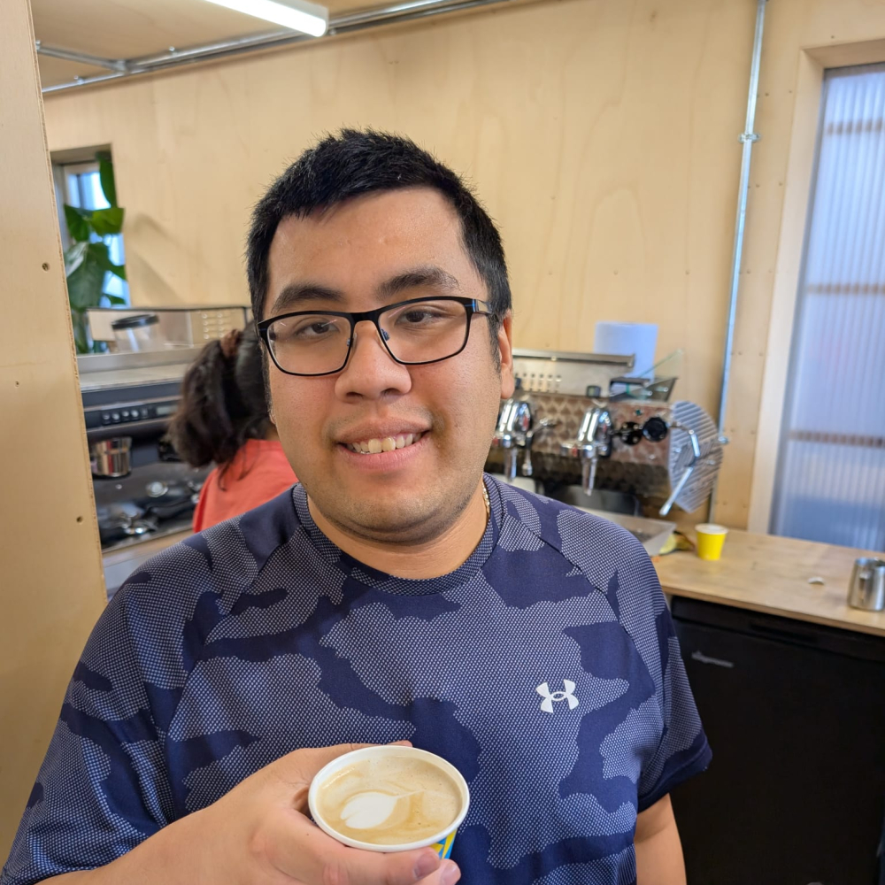 A man proudly shows off the barista style coffee he's just made
