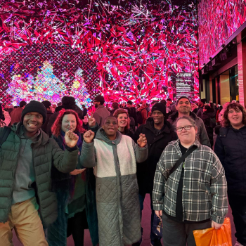 A group of people stand under pink lights