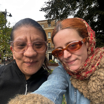 Two ladies take a selfie, they are on a befriending meetup having a walk outside, both wearing sunglasses