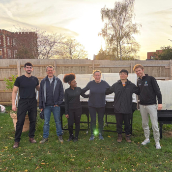 A group of corporate volunteers stand in a line in the Share garden smiling