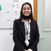 Share student Fatima stands smiling in her interview suit with hands crossed in front of her